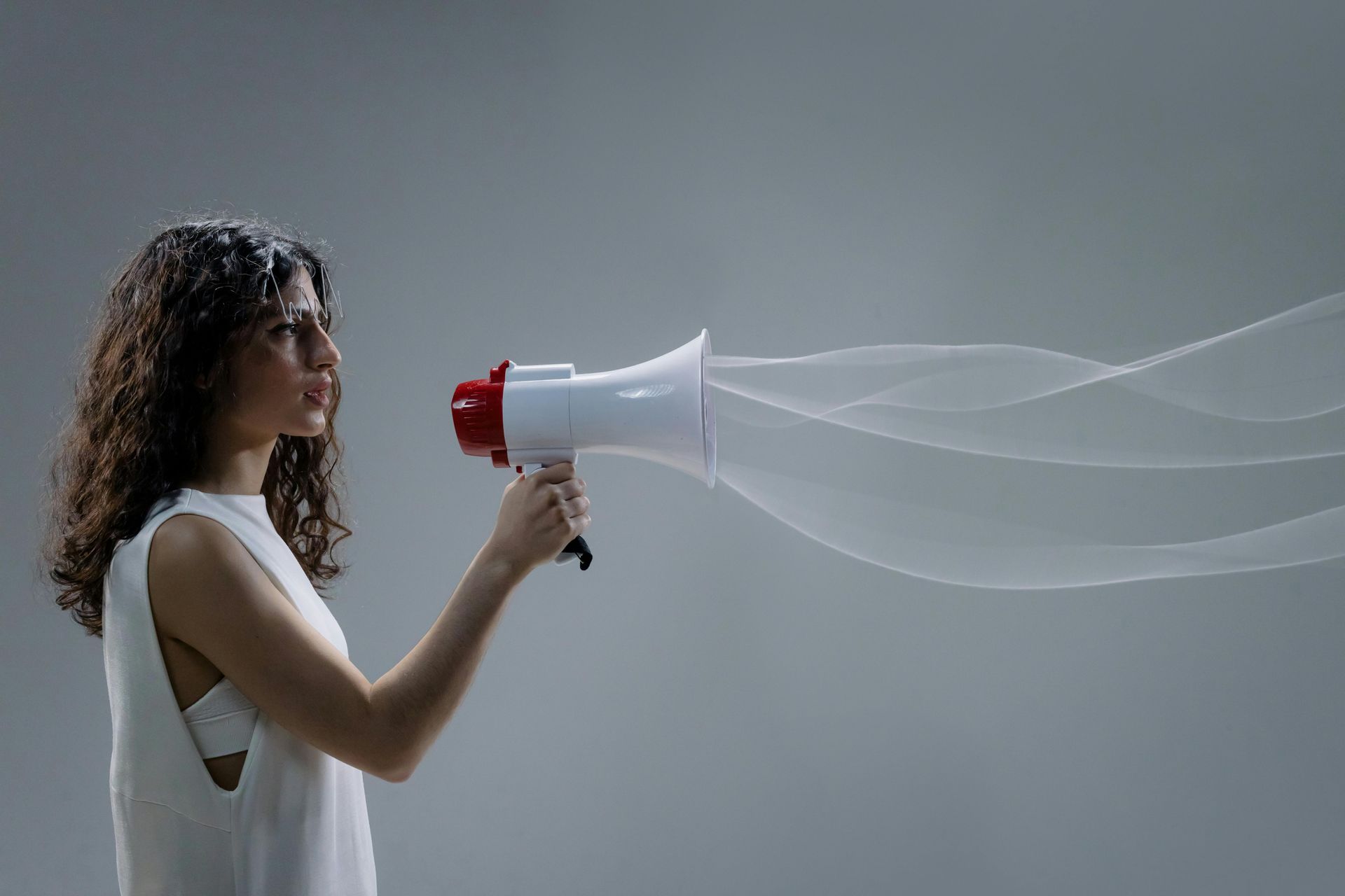 A woman is holding a megaphone with waves coming out of it.