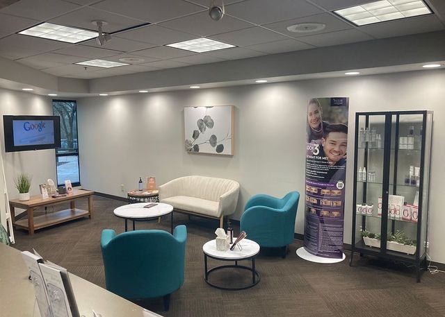 A waiting room with a couch , chairs , tables and a tv.