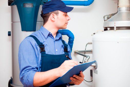 Plomero inspeccionando equipo; vistiendo mono azul, gorra, sosteniendo un portapapeles