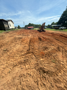 A bulldozer is digging a dirt road in a field.