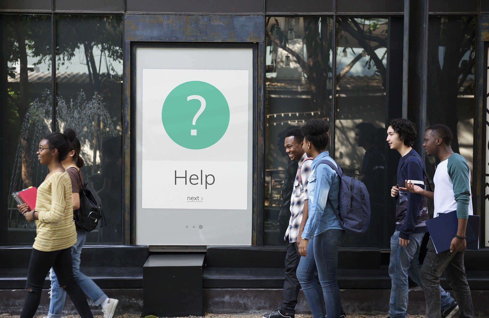 A group of people are walking past a sign that says help.