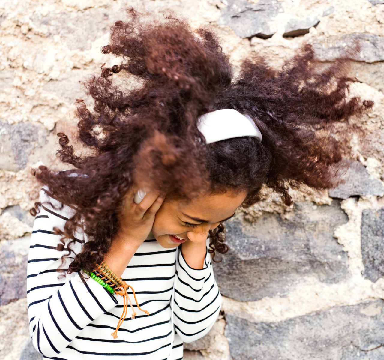 A young girl with curly hair wearing a striped shirt