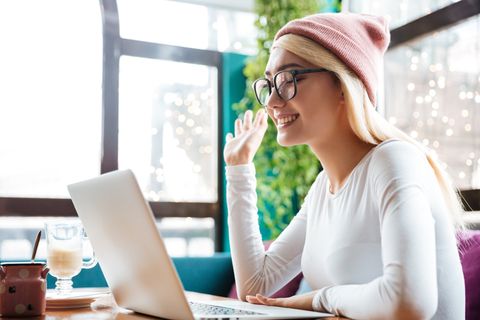 A woman is sitting at a table using a laptop computer.
