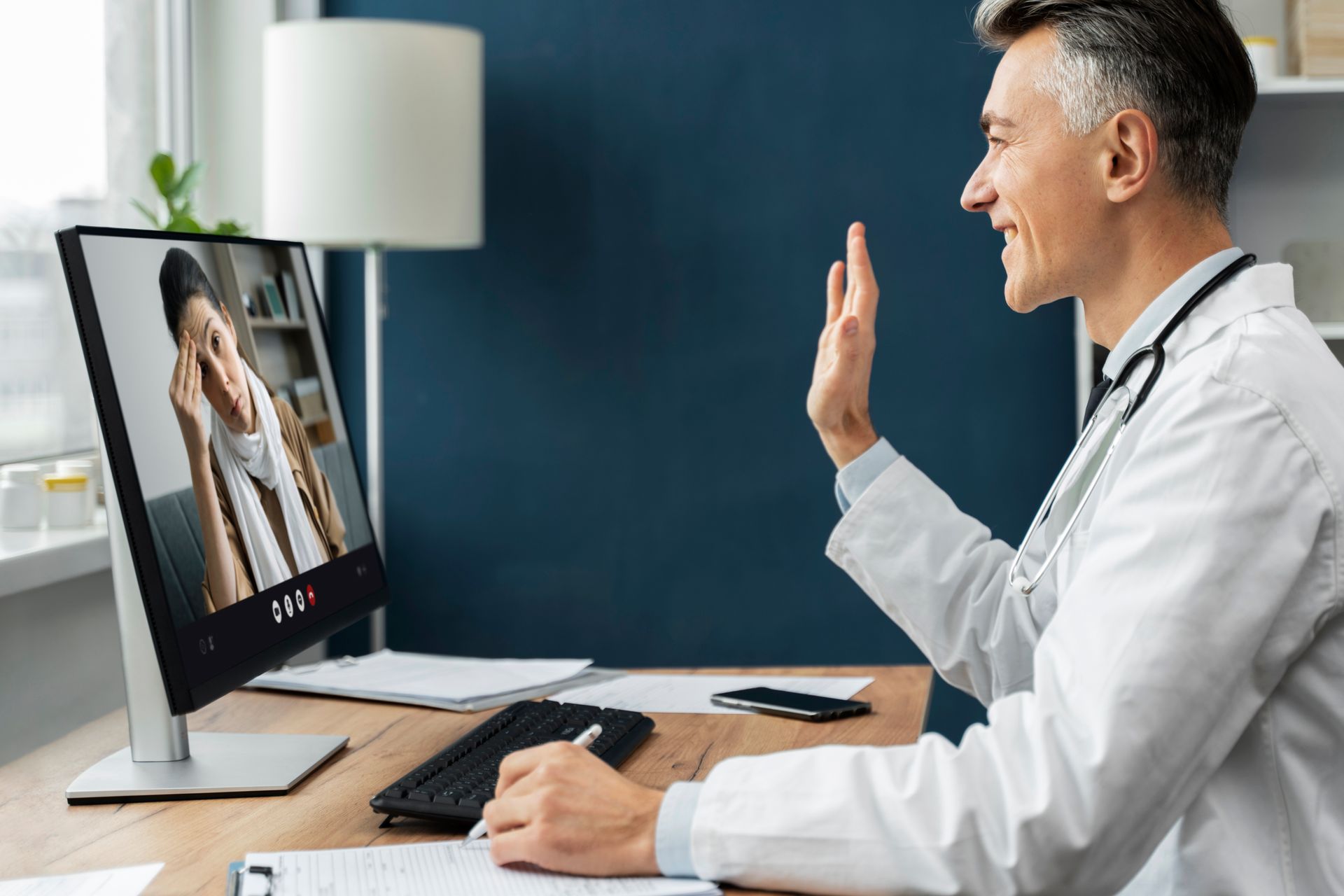 A doctor is giving a high five to a patient on a video call.