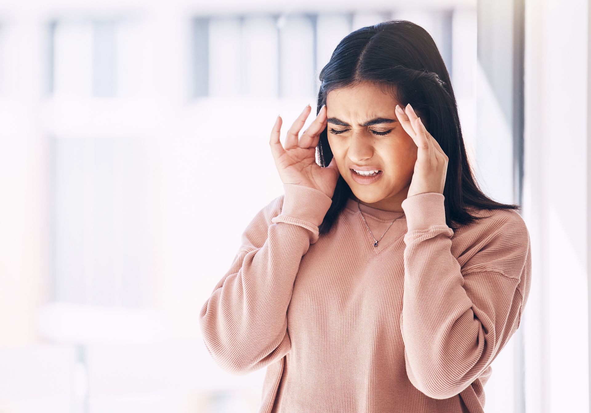 A woman is holding her head because she has a headache.