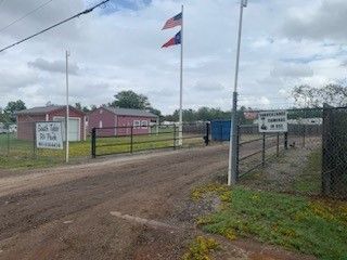a dirt road leading to a fenced in area with a flag on a pole .