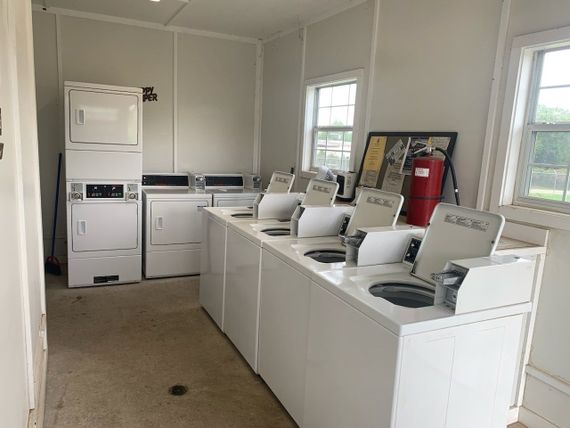 a row of white washers and dryers in a laundromat
