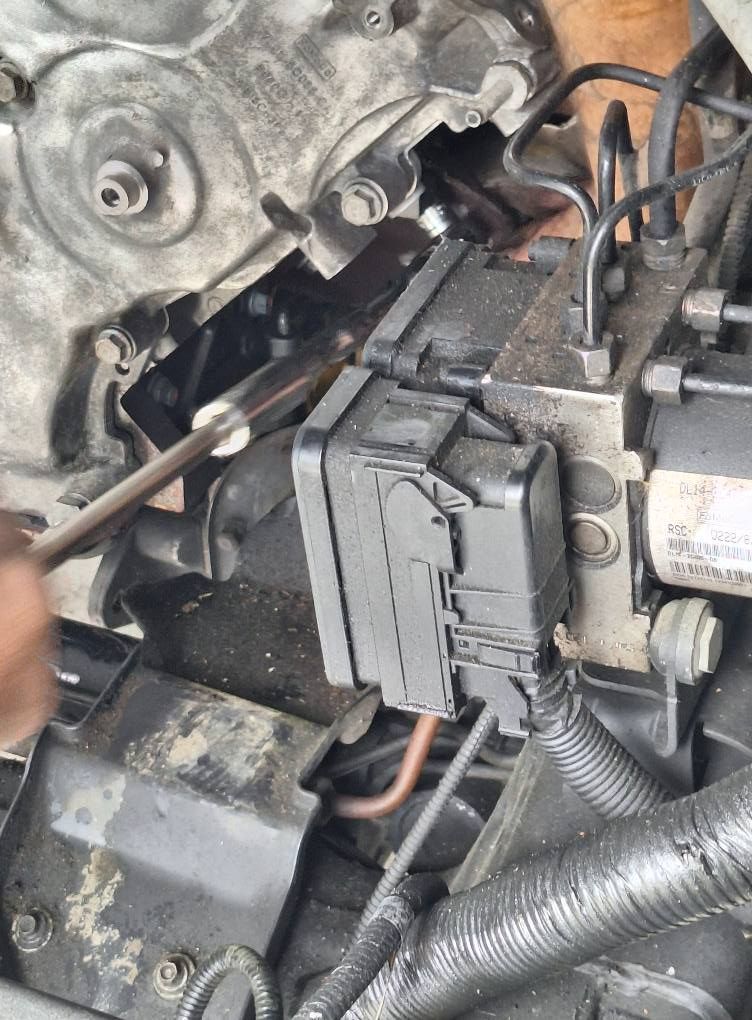 A yellow excavator is sitting on top of a pile of gravel.