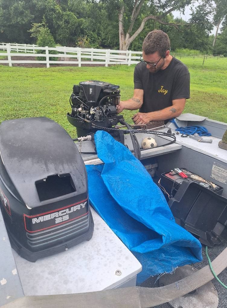 Man working on a Mercury boat motor in a small boat outdoors.