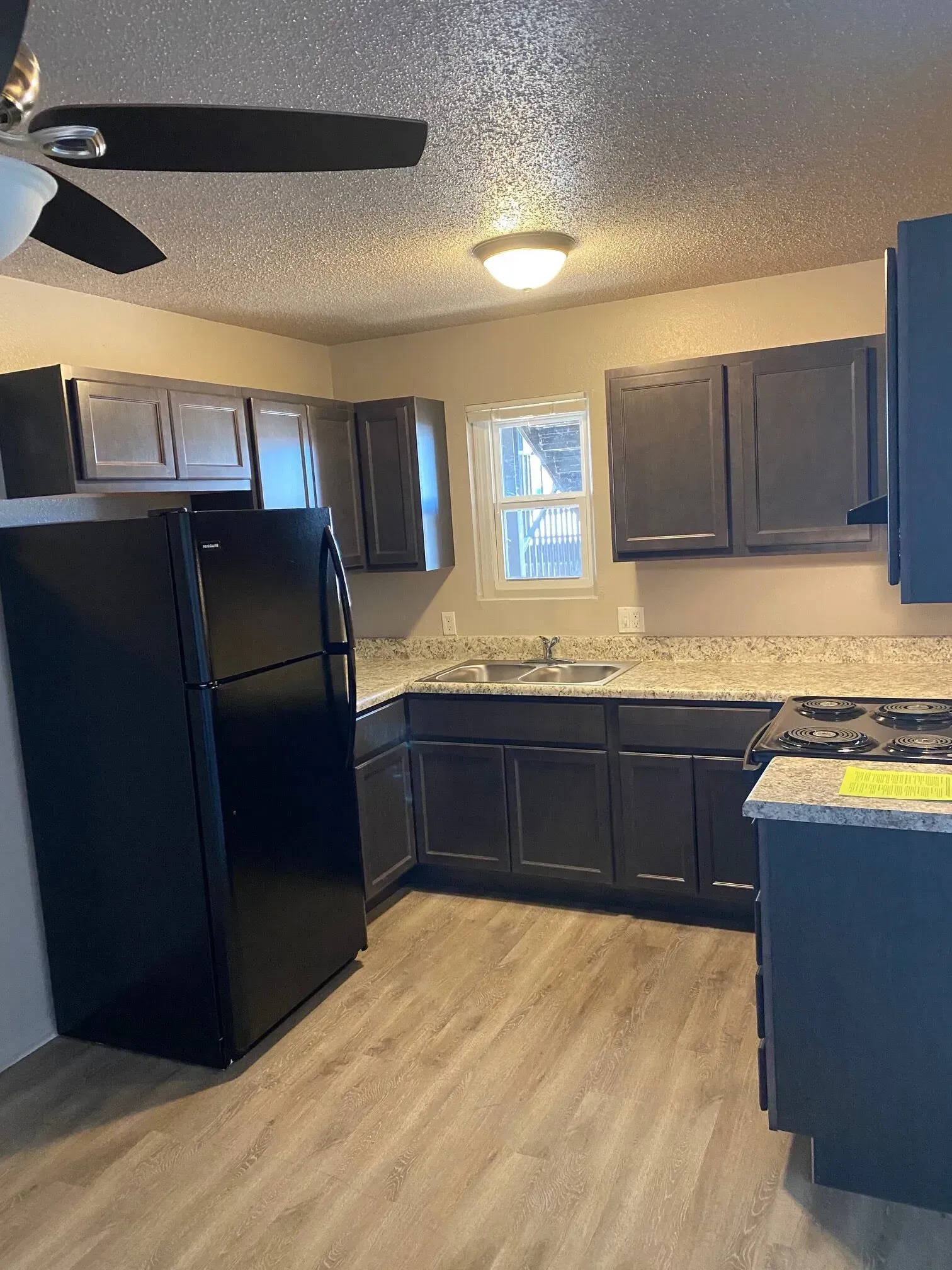 Kitchen with black cabinets, black refrigerator, and gray countertops.