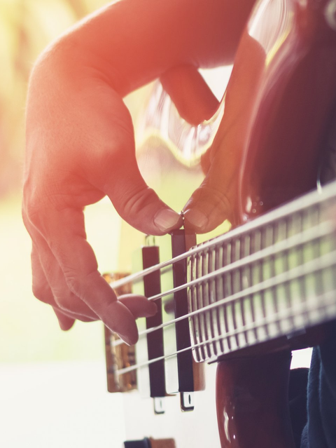 Two people, man guitar teacher working with little boy on guitar lessons.