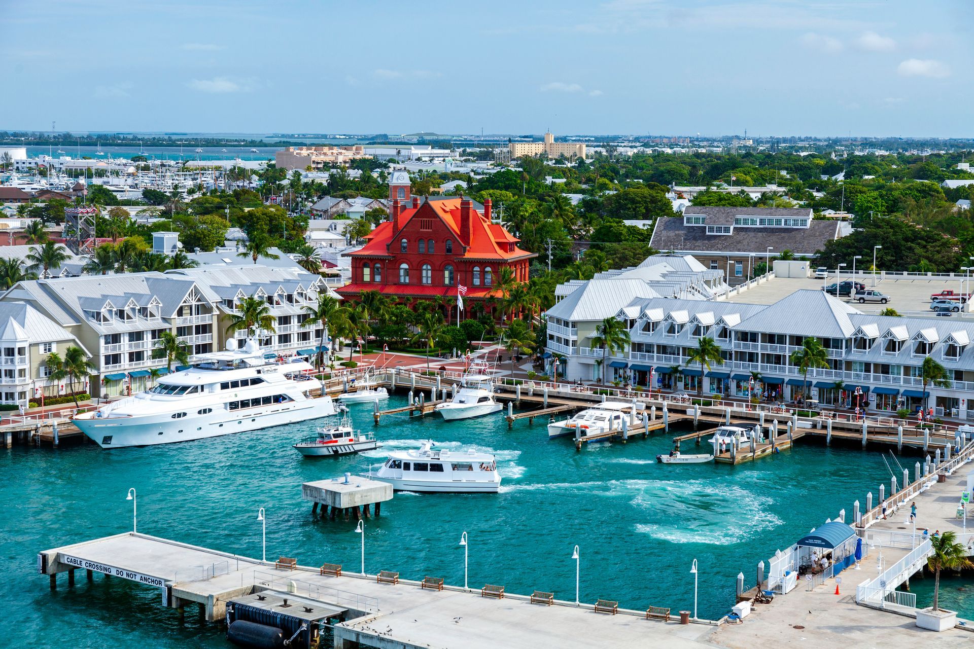 Key West harbor with boats, white buildings, red roof, and turquoise water.