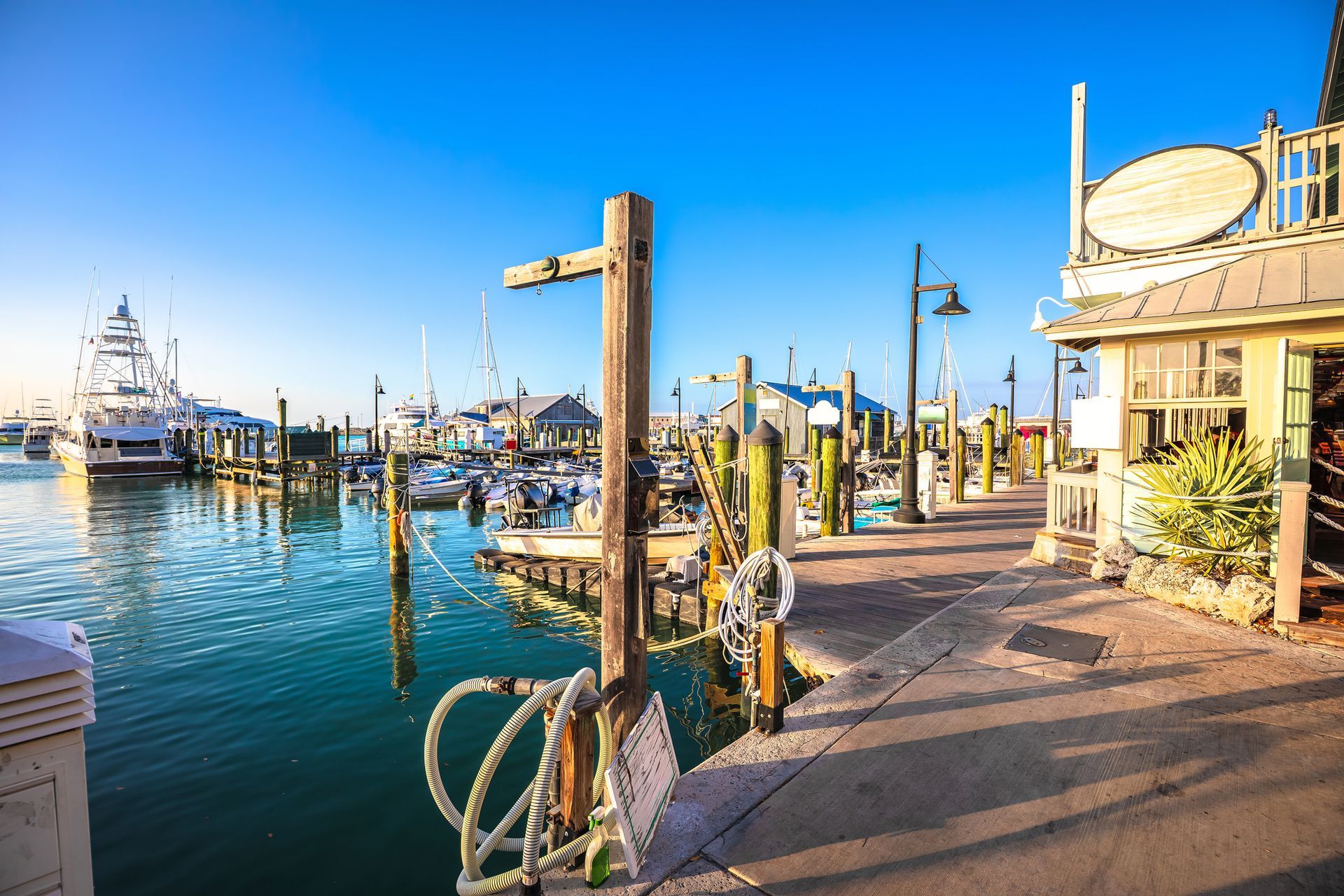 Dockside scene: boats, water, wooden posts, a building, and a sunny sky.