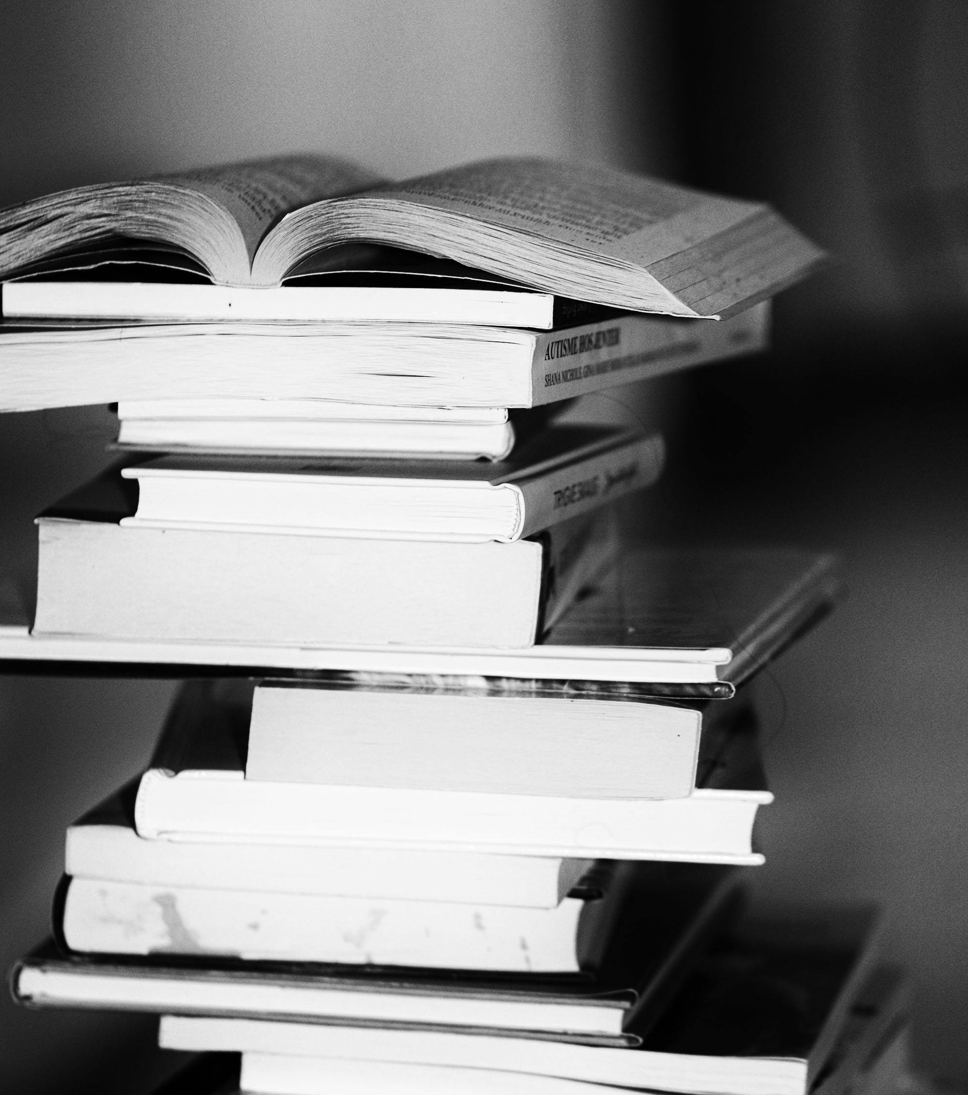 Stack of books, some open, in black and white.