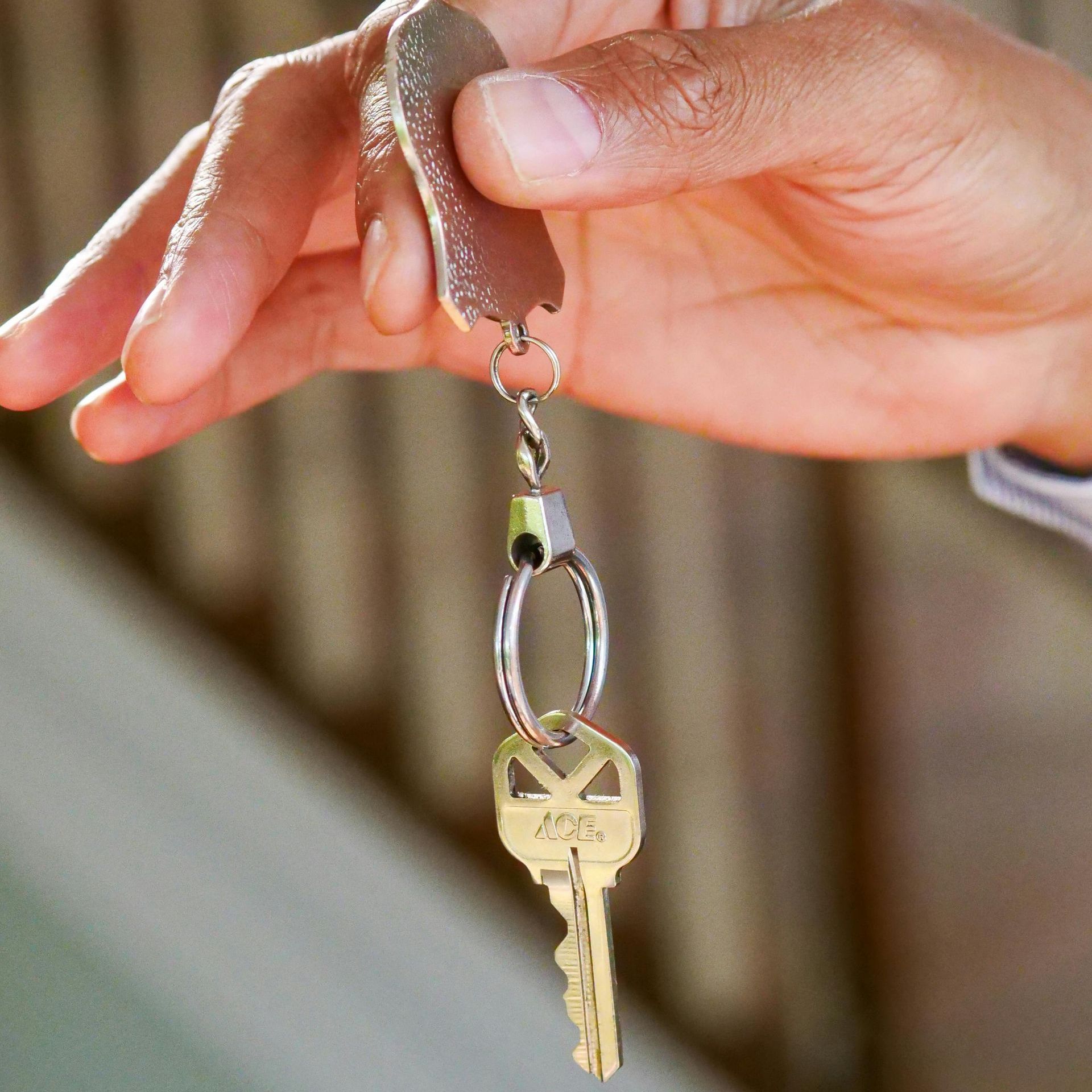 Hand holding a key on a silver key ring. A leather tag is attached to the ring.
