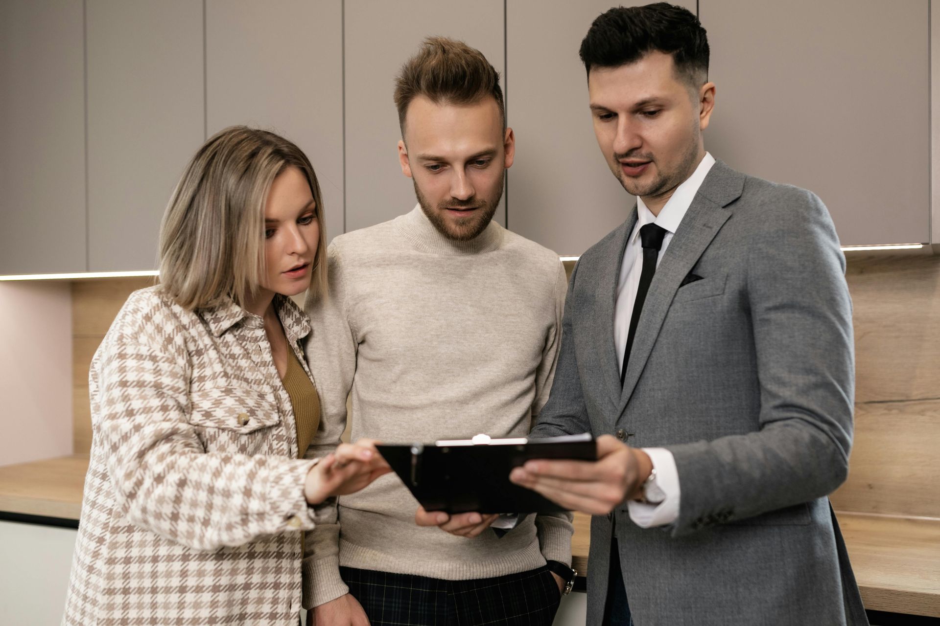 Real estate agent shows a couple documents in a modern kitchen.