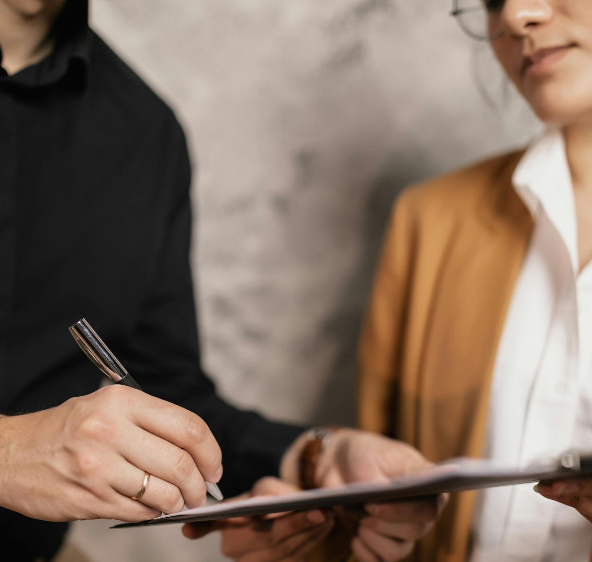 Person signing a document held by another person in a business setting.