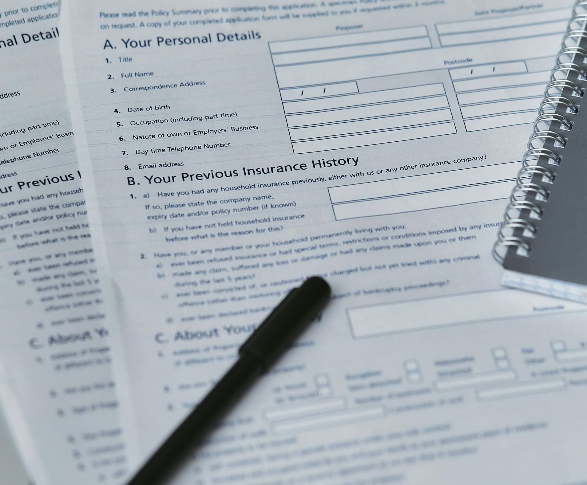 Forms, pen, and spiral notebook on a table, ready to be filled out.