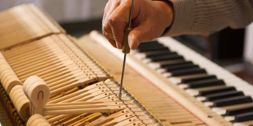 Expert checking piano for repair in Norwich, CT