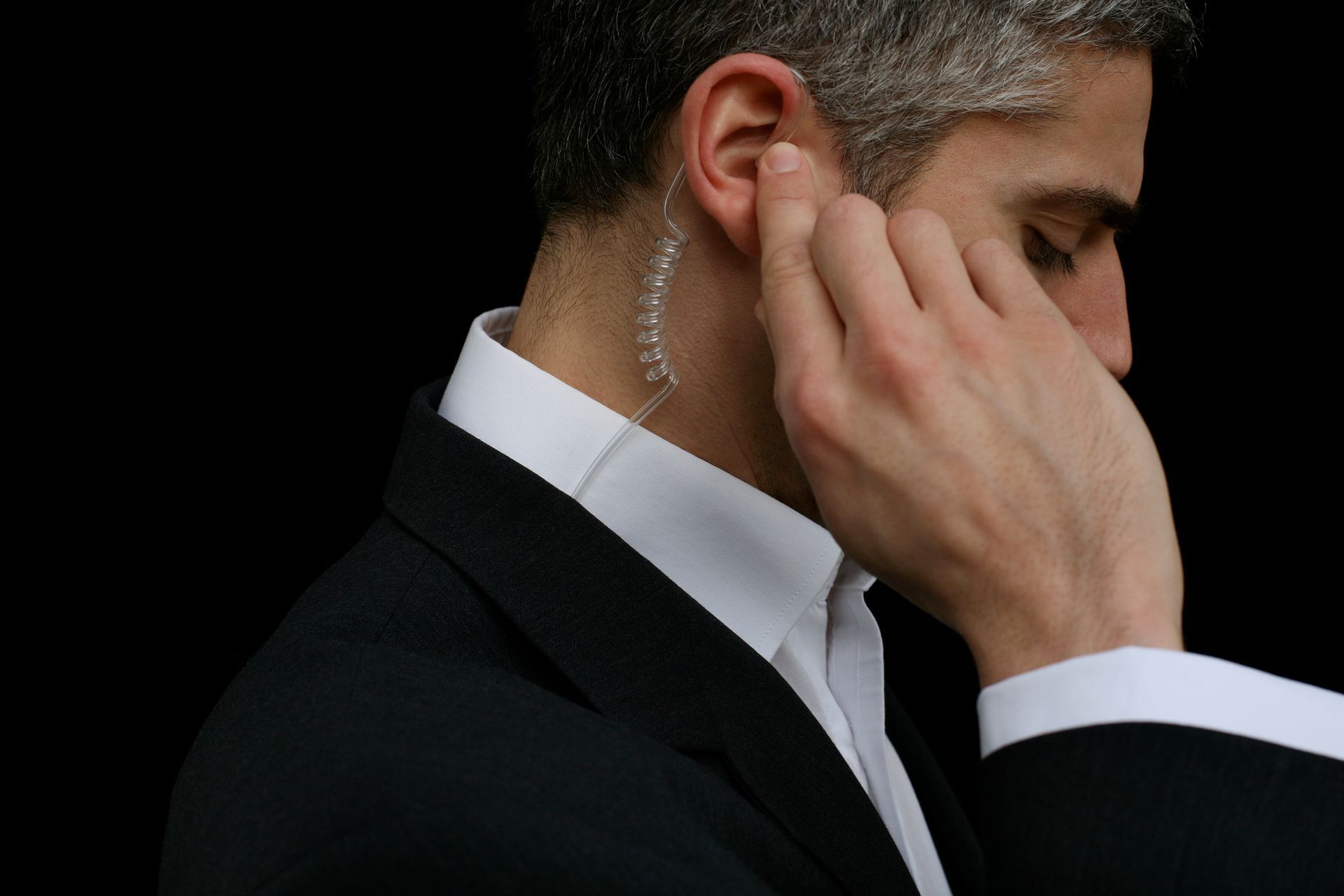 A man in a suit is covering his ear with his hand