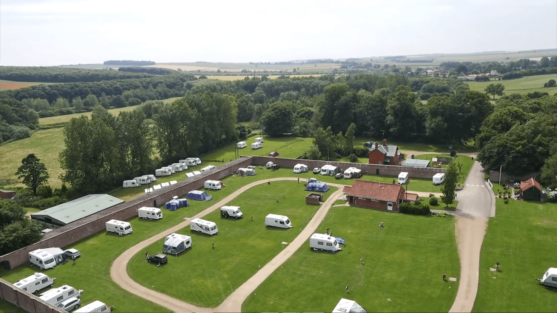 Overhead view of a campground with RVs, surrounded by trees and fields.