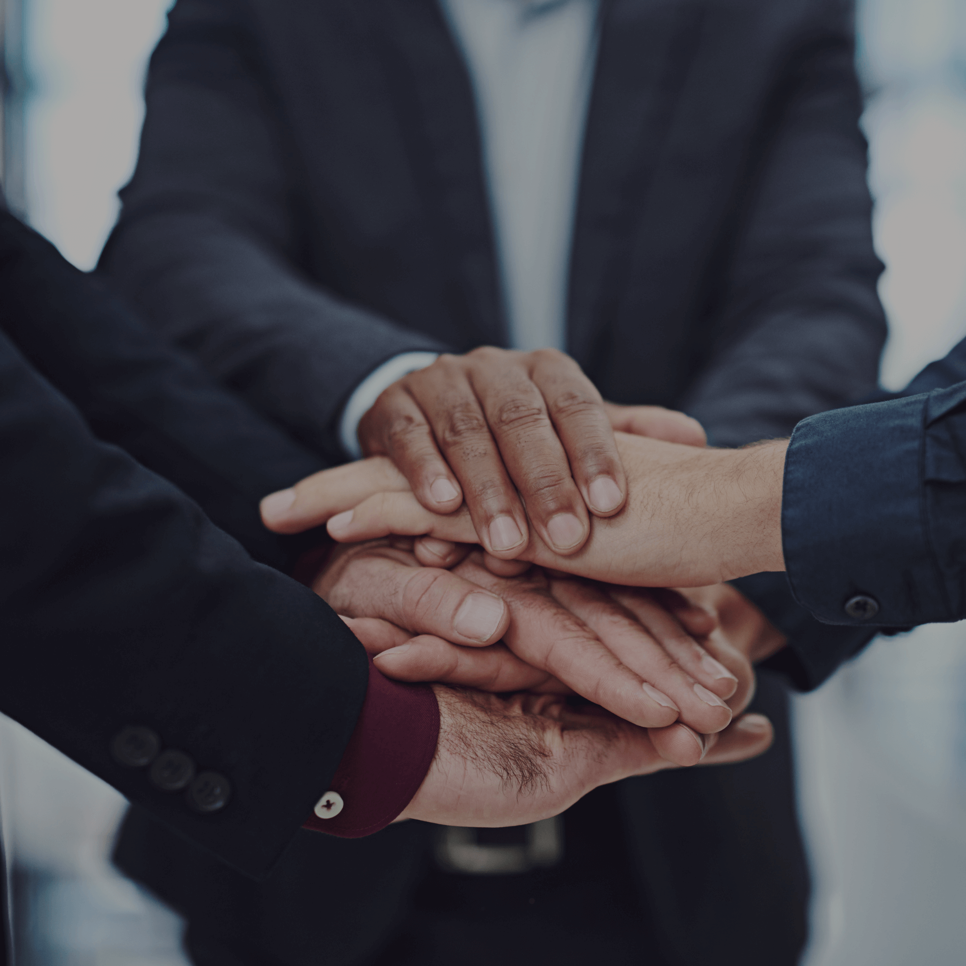 Diverse hands stacked in a huddle, symbolizing Gym Revival Group's global culture and teamwork.