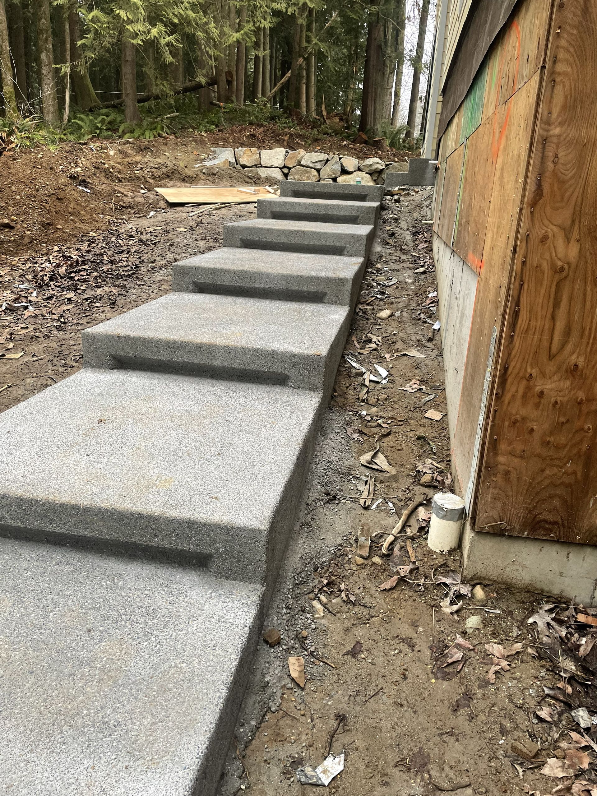 Concrete steps beside a building, leading up a gravel path in a wooded area