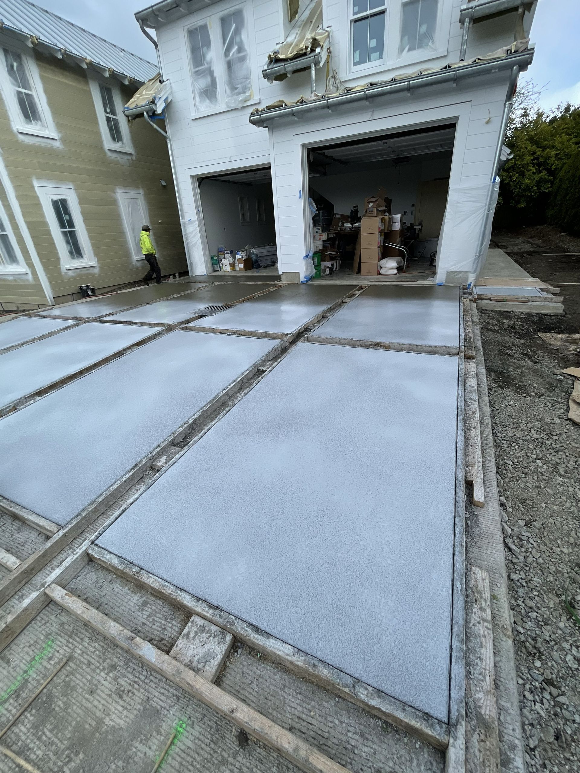 Concrete driveway slabs leading to an open garage of a two-story house