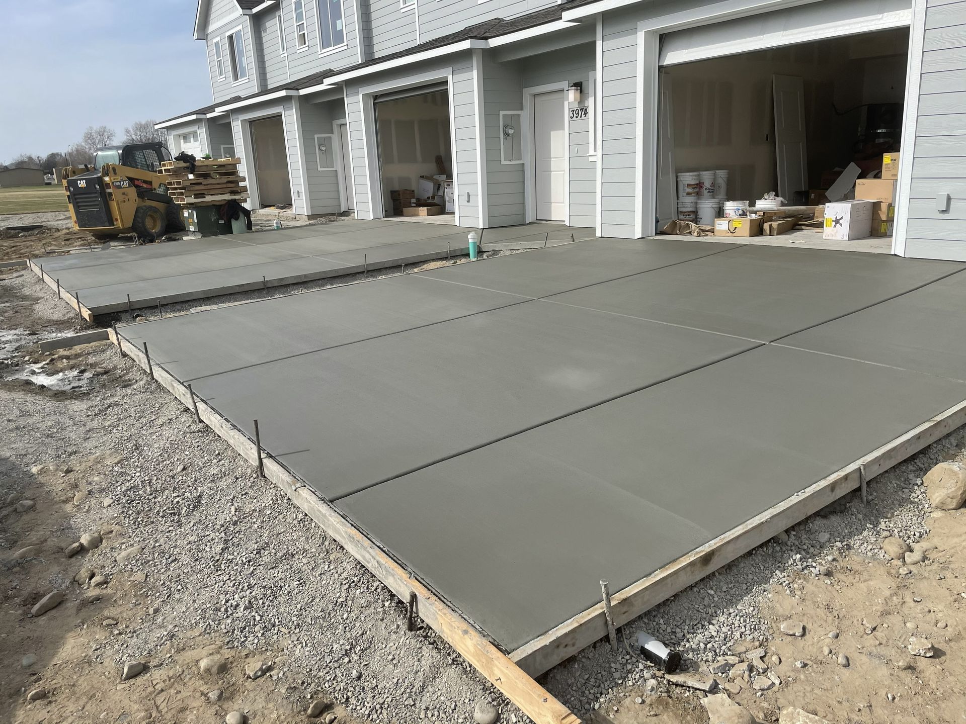 Freshly poured concrete driveway slabs outside a row of garage units during construction