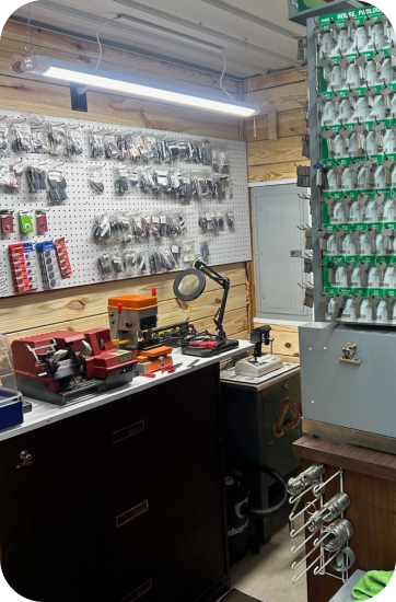 A locksmith shop with key cutting tools, key racks, and a safe. The walls are wood-paneled | Chip Ragans Auto, LLC