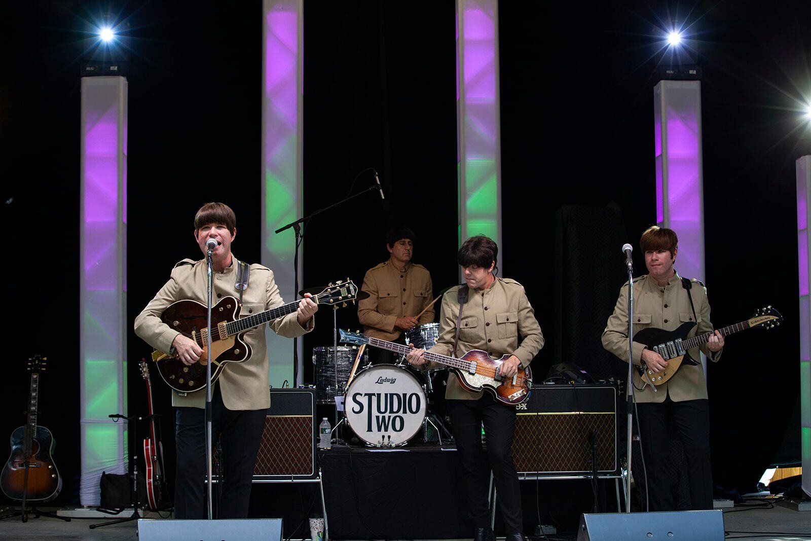 A group of men are playing guitars and singing on a stage.