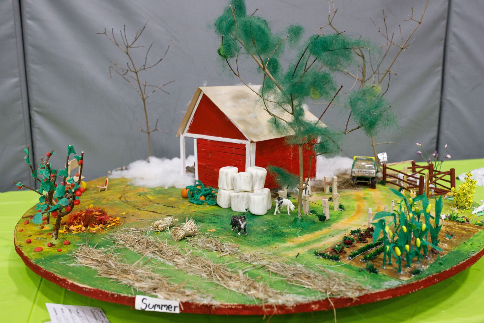 A model of a farm with a red barn and hay bales