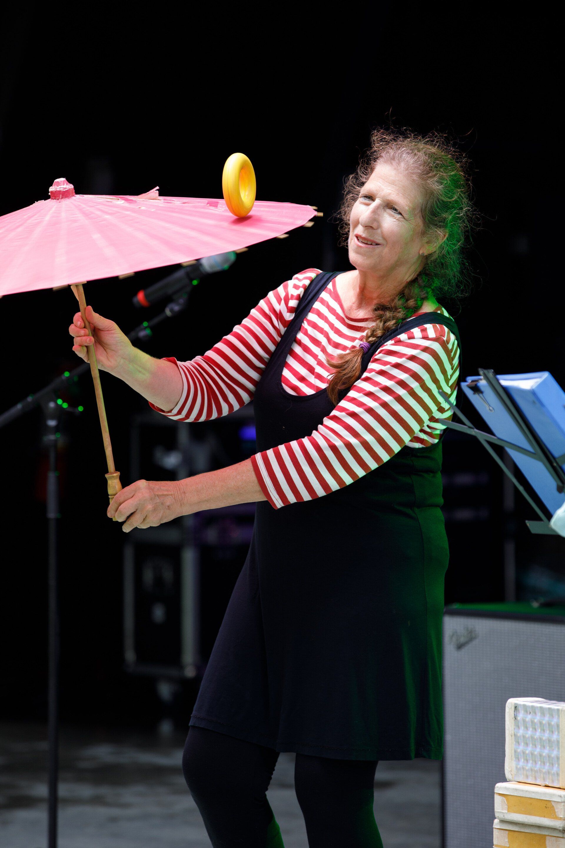 A woman is holding a pink umbrella with a banana on top of it.