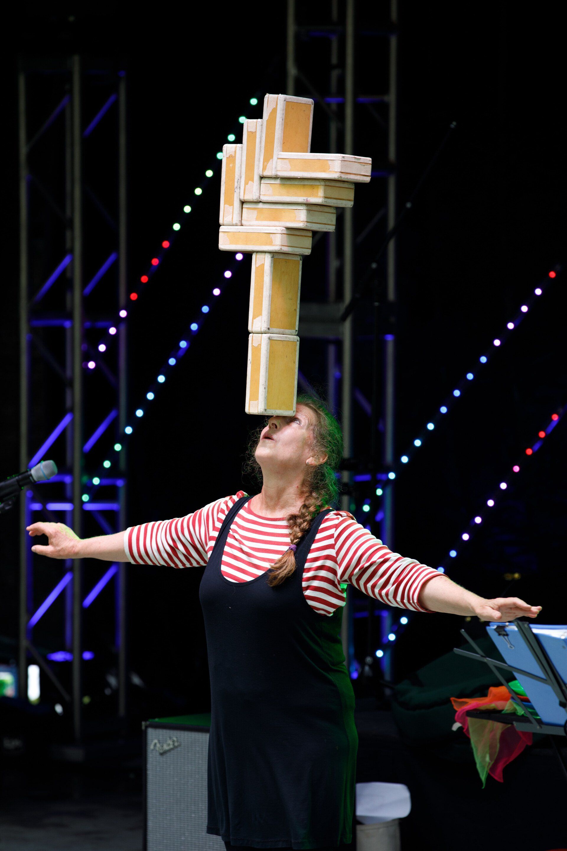 A woman is balancing a stack of boxes on her head.