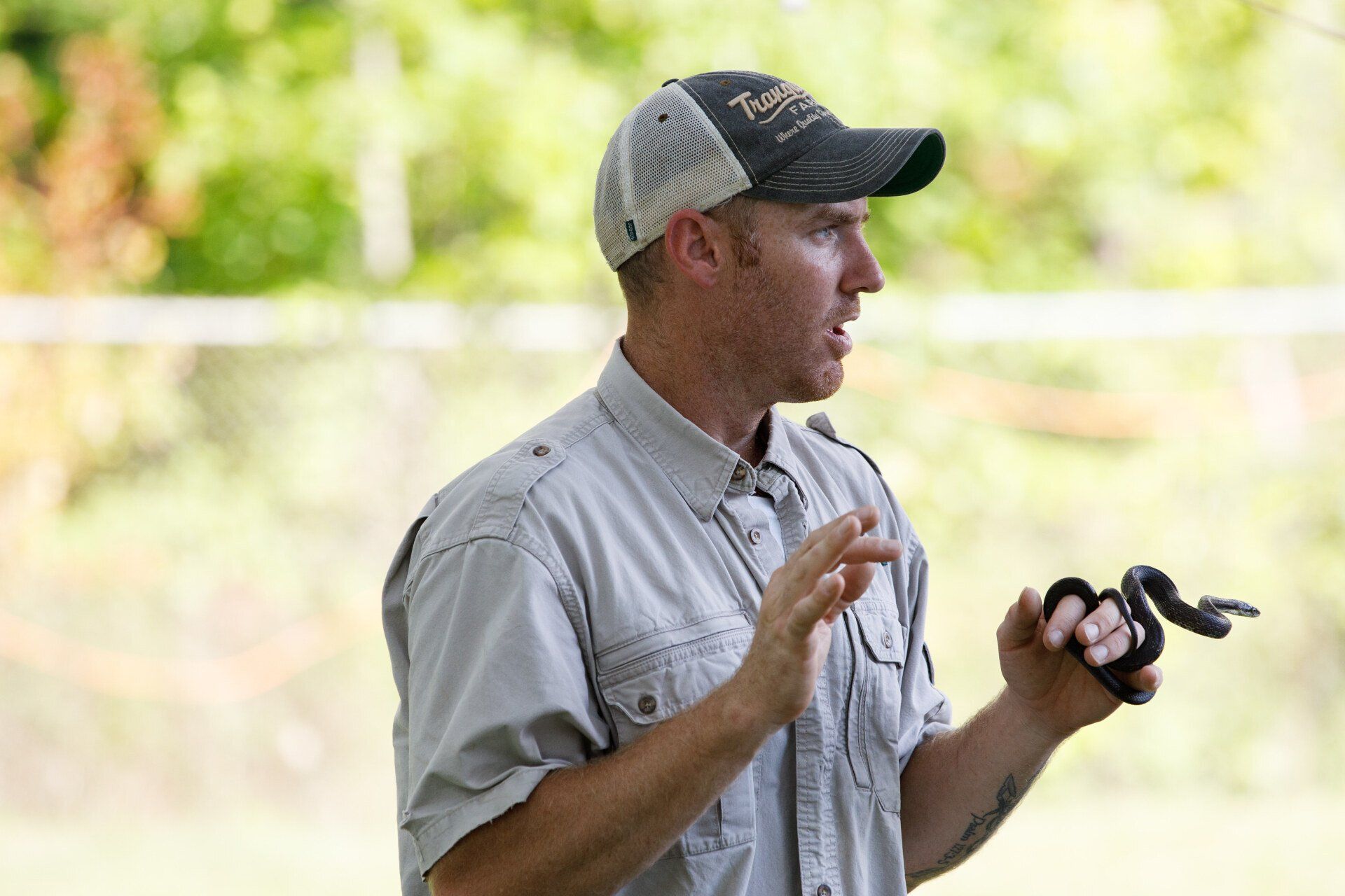 A man in a hat is holding a snake in his hand.