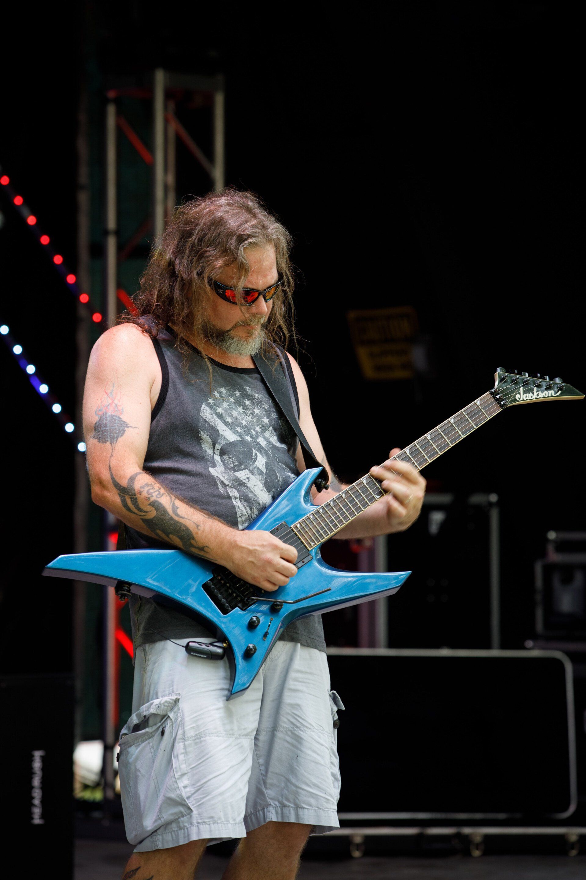 A man is playing a blue electric guitar on a stage.