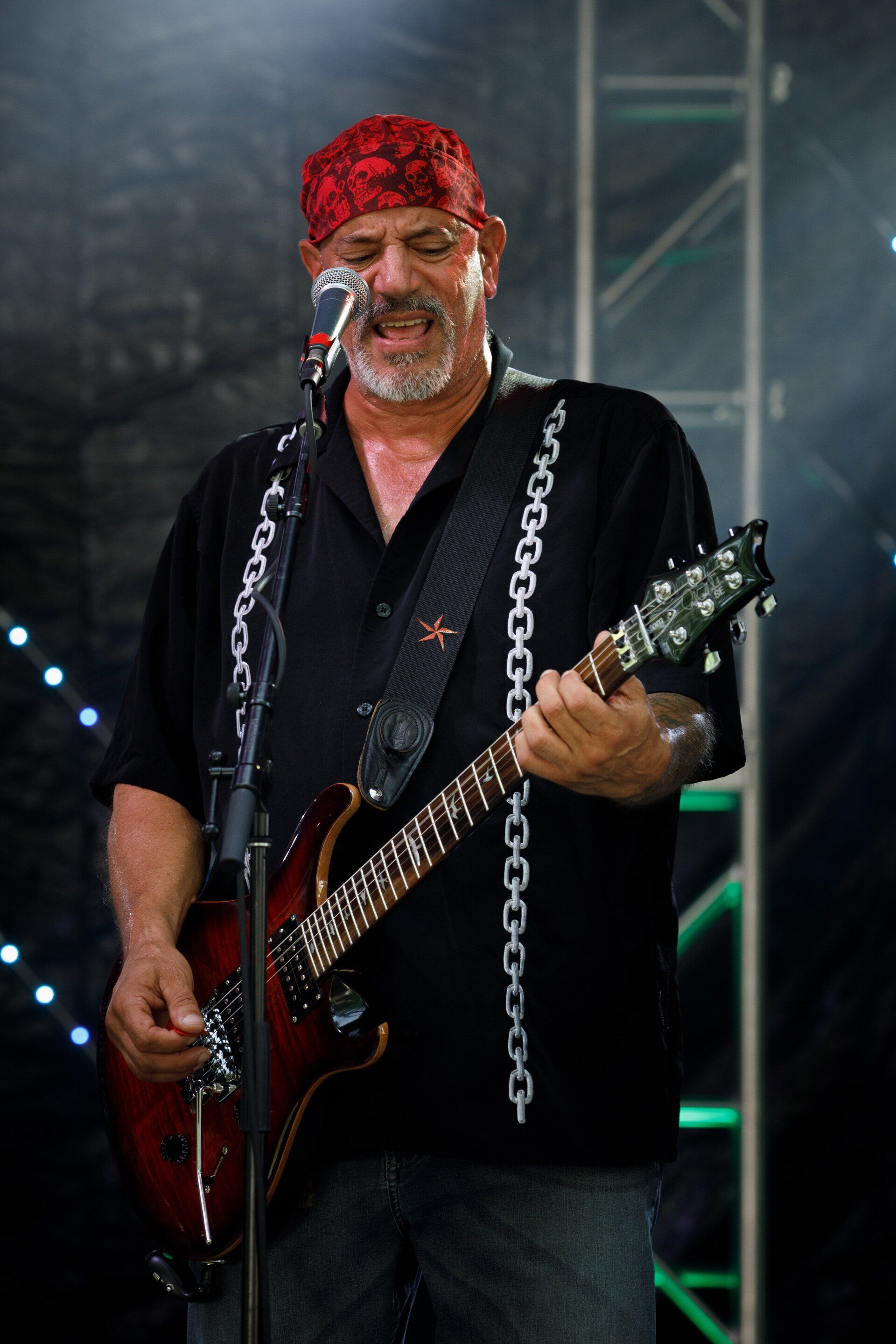 A man singing into a microphone while playing a guitar