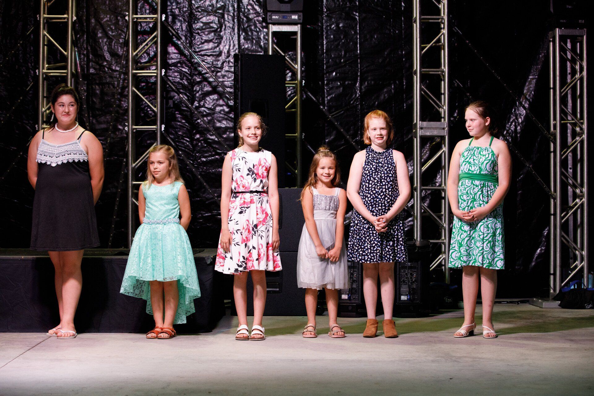A group of young girls are standing next to each other on a stage.