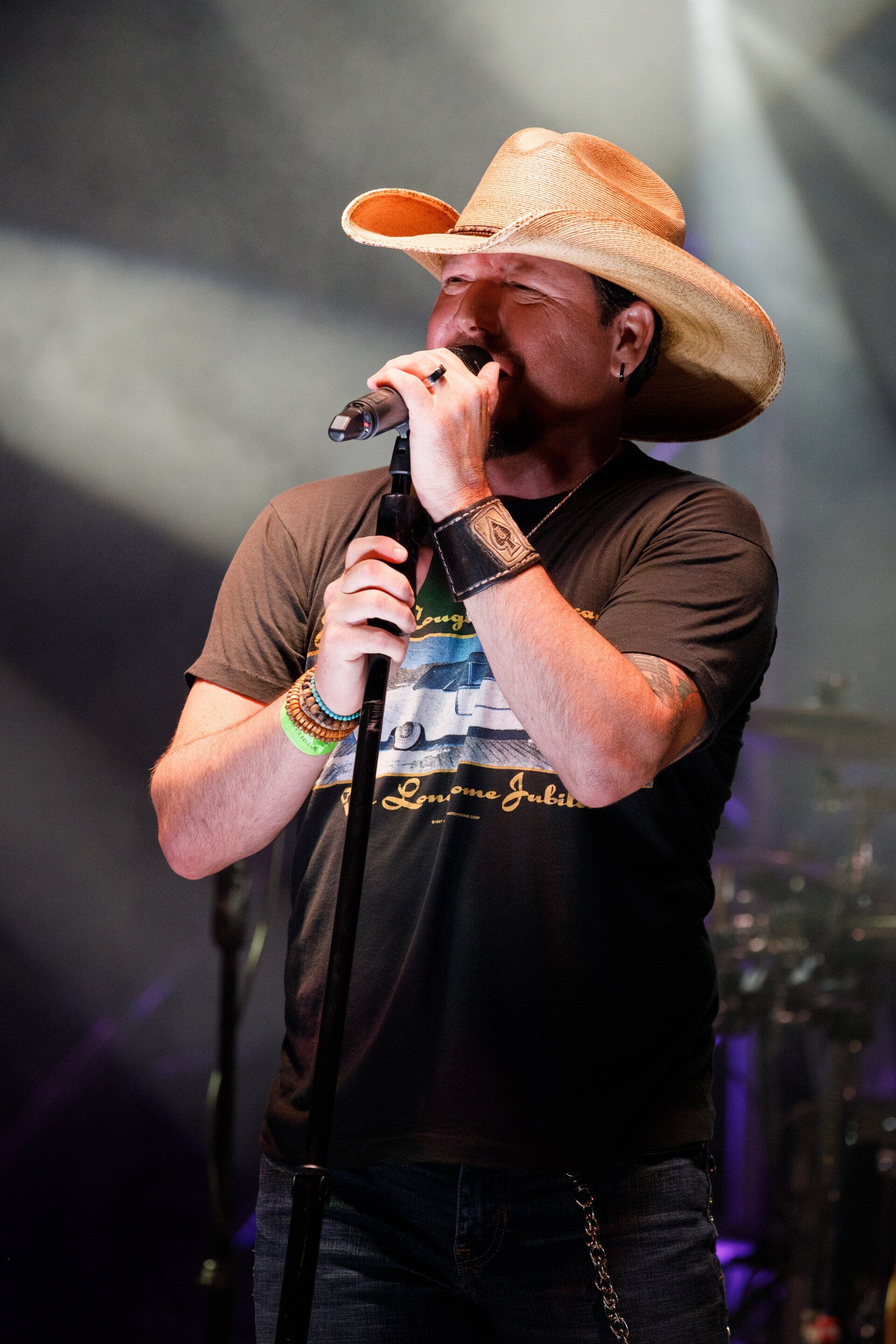 A man wearing a cowboy hat is singing into a microphone.