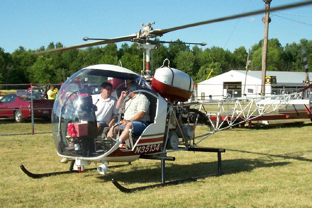 A small helicopter is parked in a grassy field