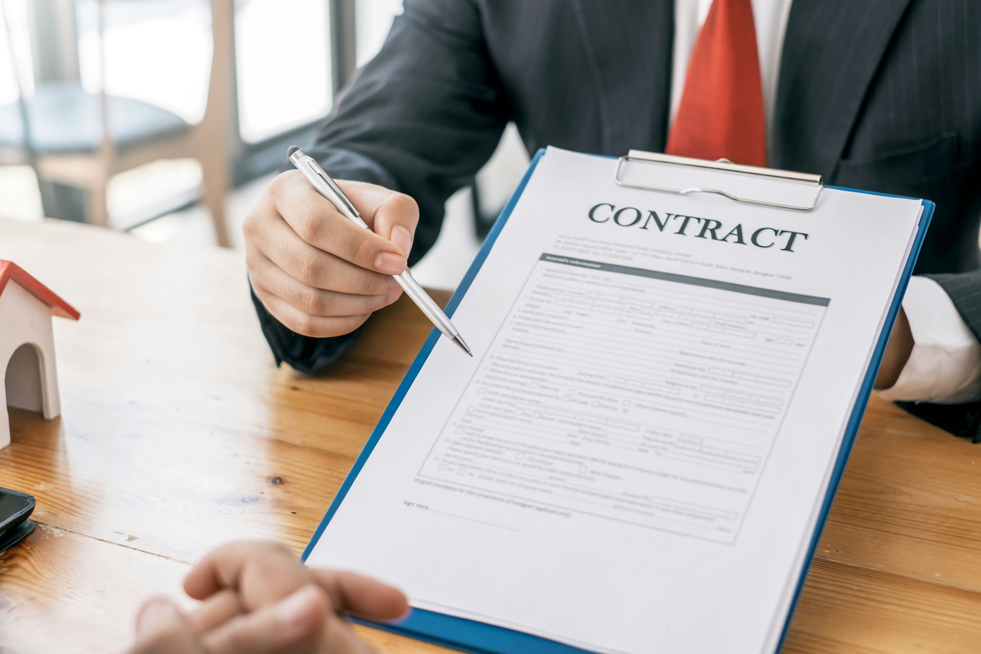 A man in a suit and tie is signing a contract on a clipboard.