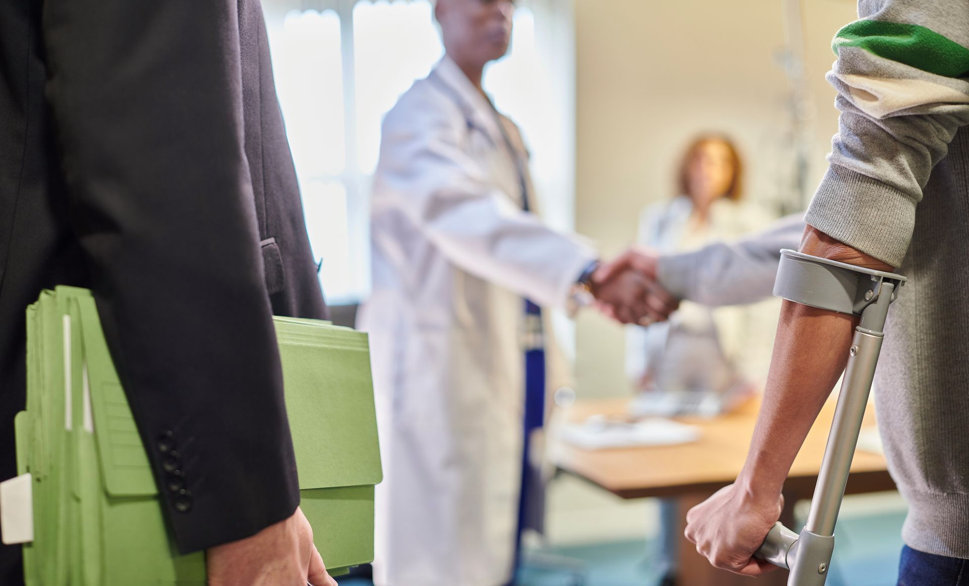 A man with crutches is shaking hands with a doctor.