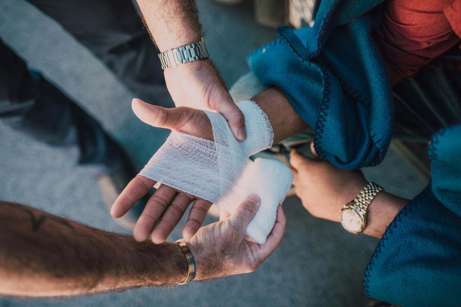 A person is wrapping another person 's hand with a bandage.