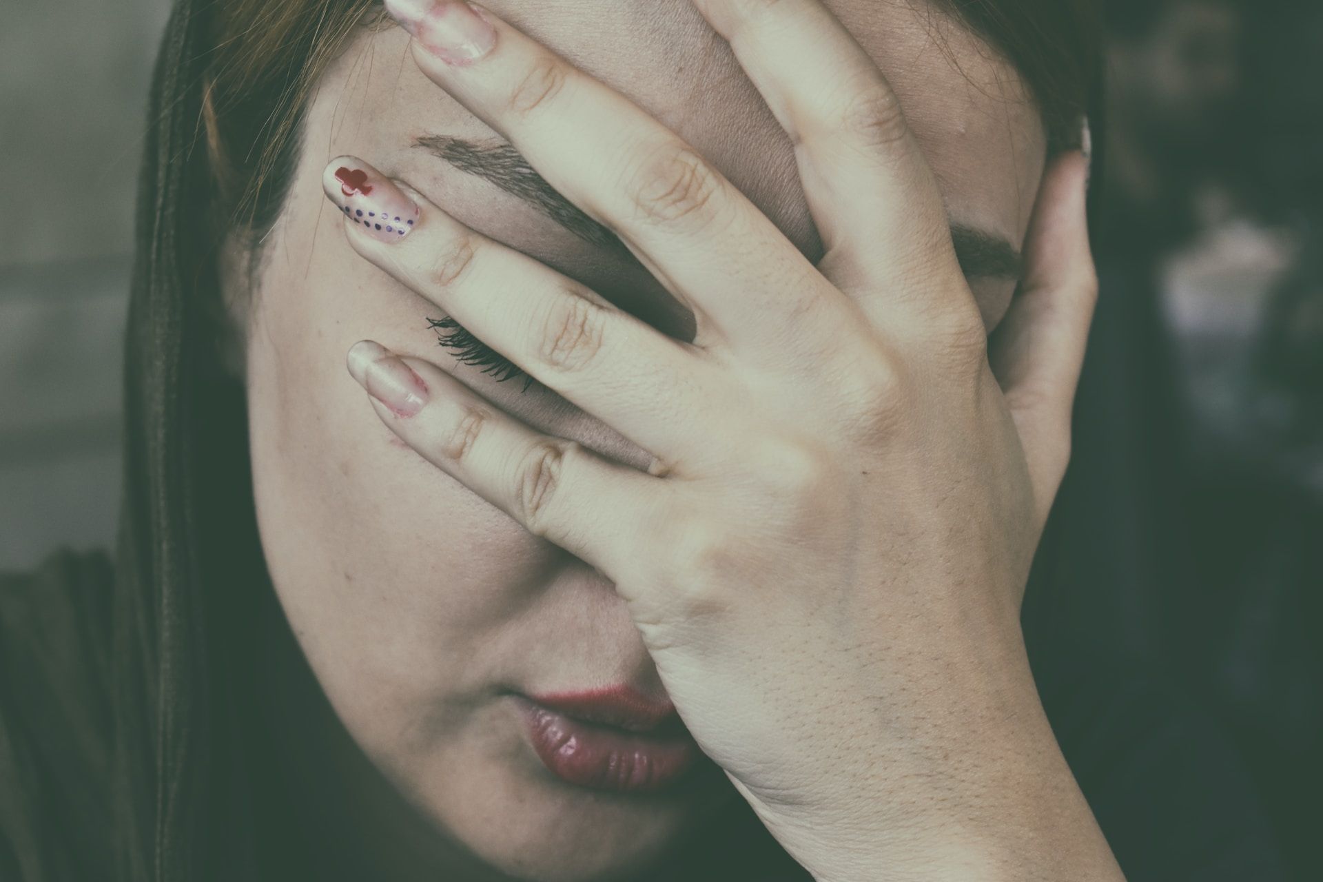 woman feeling pain while covering face with hand