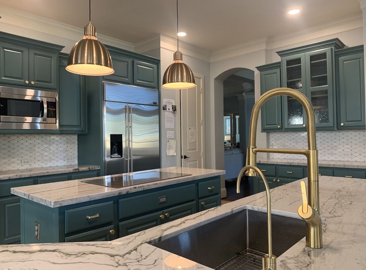 A kitchen with green cabinets , white counter tops , a sink , and a refrigerator.