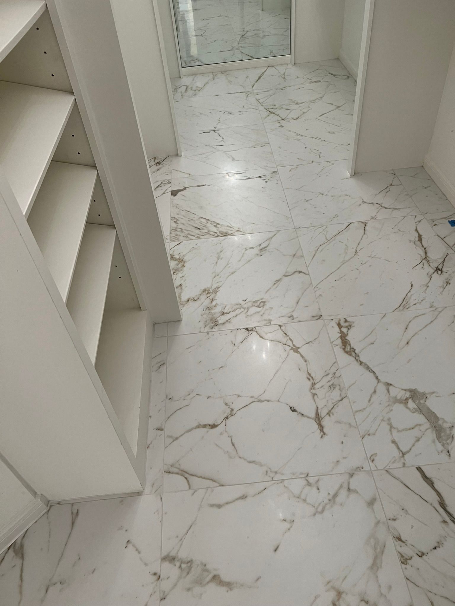 White marble tile floor with a bookcase on the left and a doorway in the background.