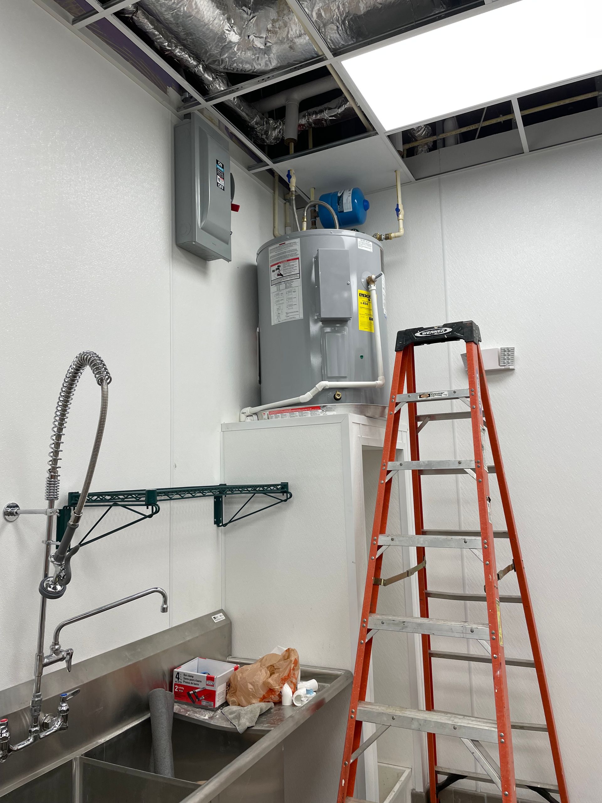 A person is fixing a water heater with a wrench.