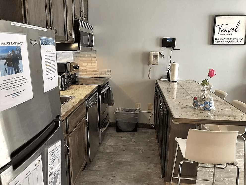 A kitchen with a stainless steel refrigerator and a granite counter top.