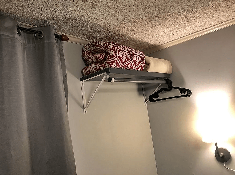 There is a shelf with clothes on it in a room.