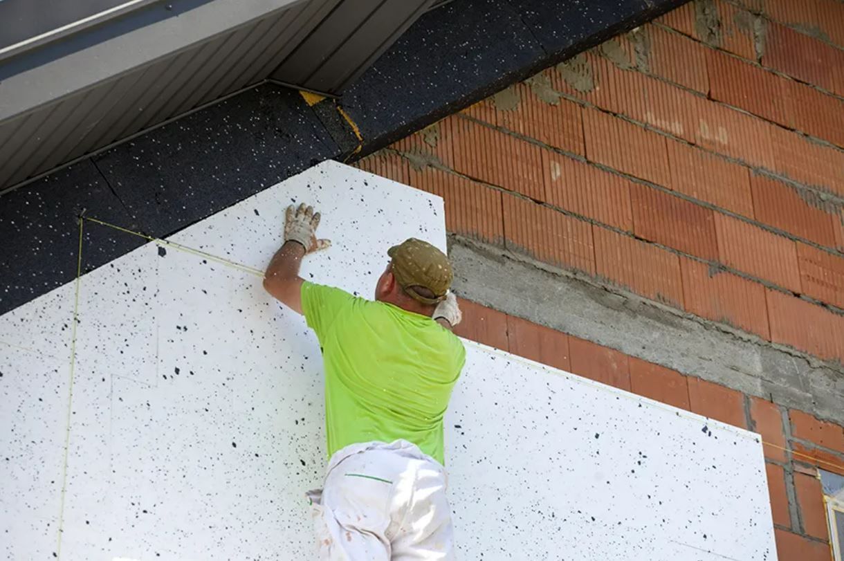 A man in a green shirt is laying on a piece of styrofoam.